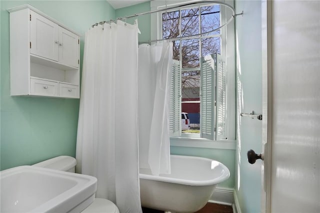 bathroom with a shower with shower curtain, toilet, baseboards, and a tub