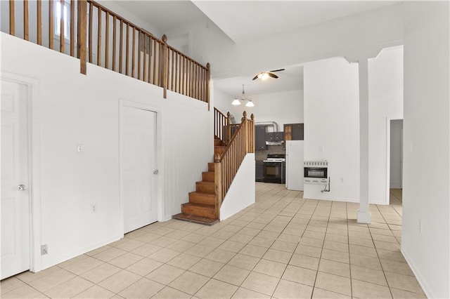 unfurnished living room with a notable chandelier, a high ceiling, light tile patterned flooring, and stairs