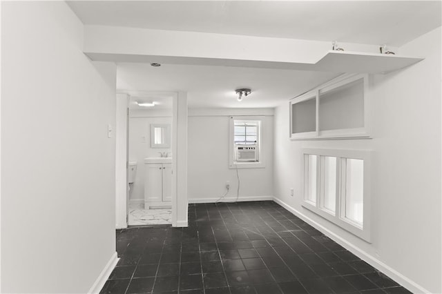 spare room featuring cooling unit, baseboards, and a sink