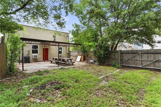 view of yard featuring a fenced backyard, central AC unit, and a patio