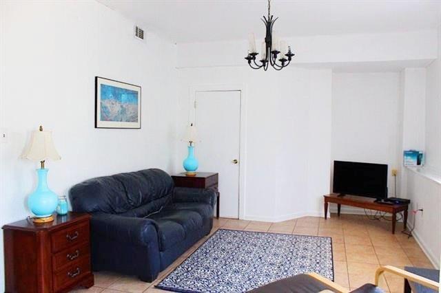 living area with an inviting chandelier, light tile patterned floors, and visible vents