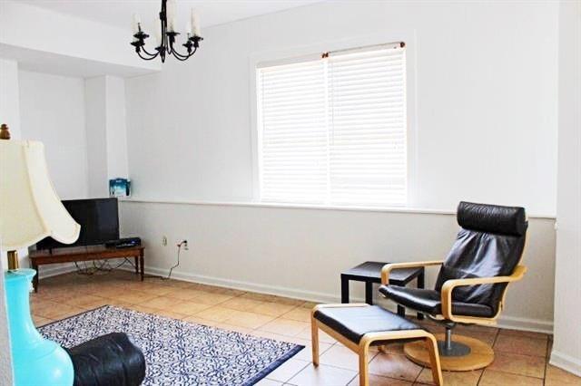 sitting room featuring tile patterned flooring, baseboards, and an inviting chandelier