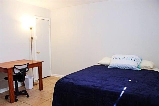 bedroom with light tile patterned floors and baseboards