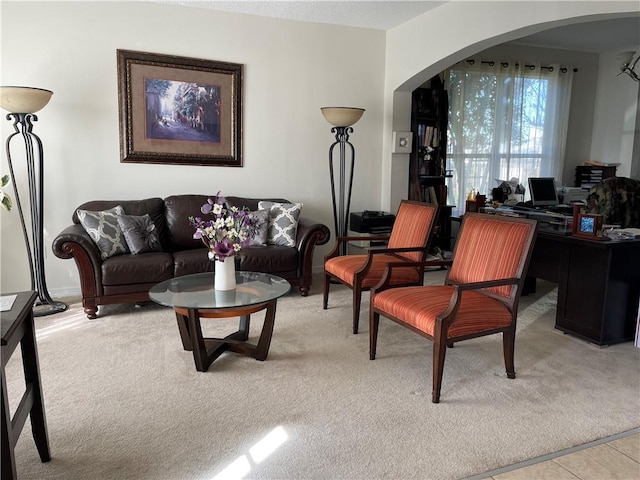 living room featuring arched walkways, light colored carpet, and light tile patterned flooring