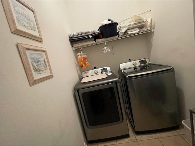 clothes washing area featuring independent washer and dryer, light tile patterned flooring, and laundry area