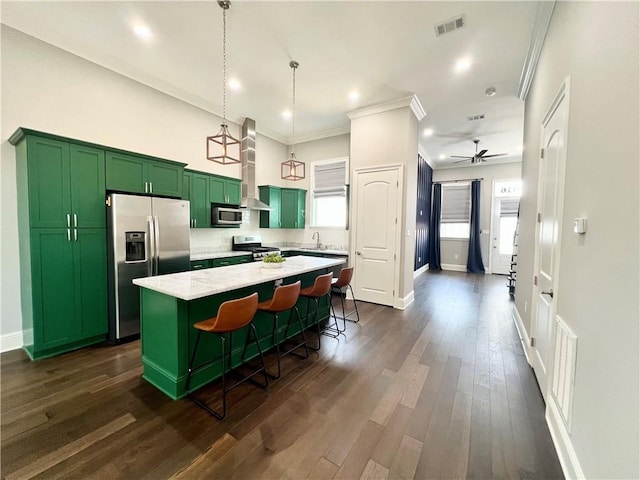 kitchen featuring green cabinetry, appliances with stainless steel finishes, a center island, a kitchen bar, and visible vents