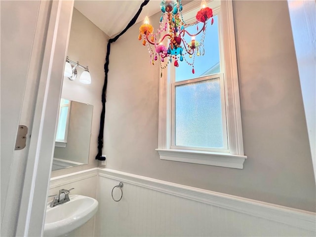 bathroom with a notable chandelier, wainscoting, and a sink