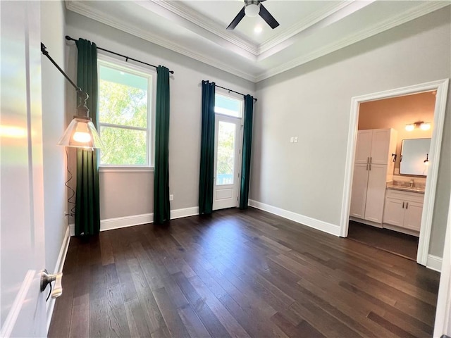 unfurnished bedroom with dark wood-style flooring, a sink, a raised ceiling, baseboards, and ornamental molding
