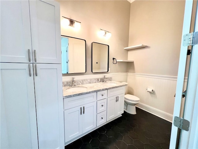 full bathroom featuring a sink, a wainscoted wall, toilet, and double vanity