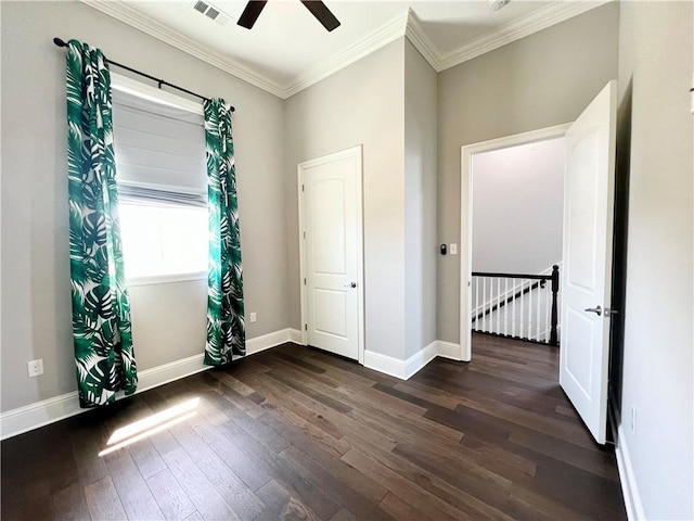 empty room with a ceiling fan, visible vents, dark wood finished floors, baseboards, and ornamental molding