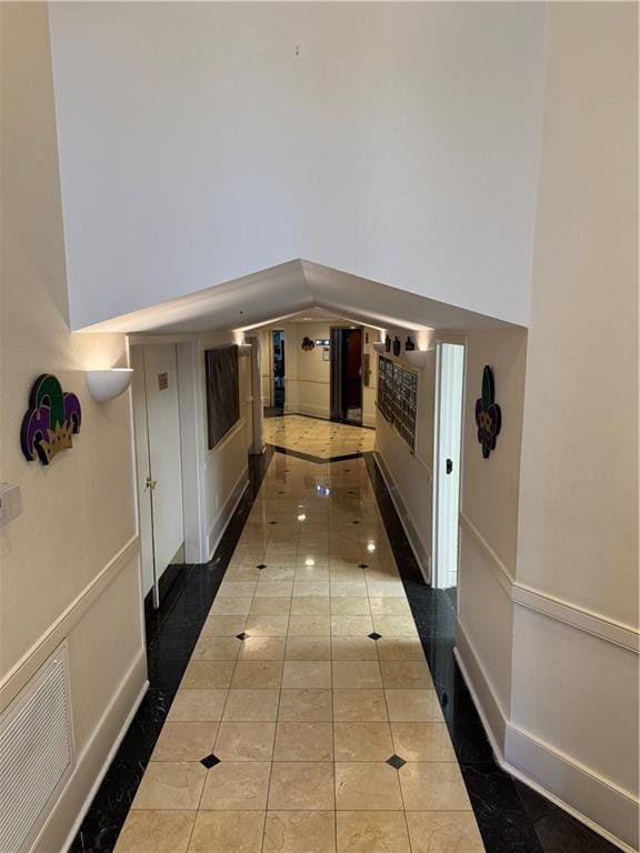 corridor with tile patterned flooring, a high ceiling, baseboards, and visible vents