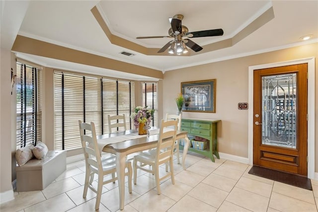 dining area featuring visible vents, baseboards, ornamental molding, a raised ceiling, and a ceiling fan