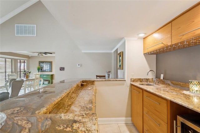 kitchen with visible vents, beverage cooler, a sink, light tile patterned floors, and light stone countertops