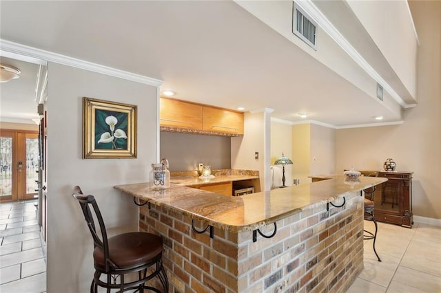 bar with light tile patterned floors, visible vents, bar area, and ornamental molding