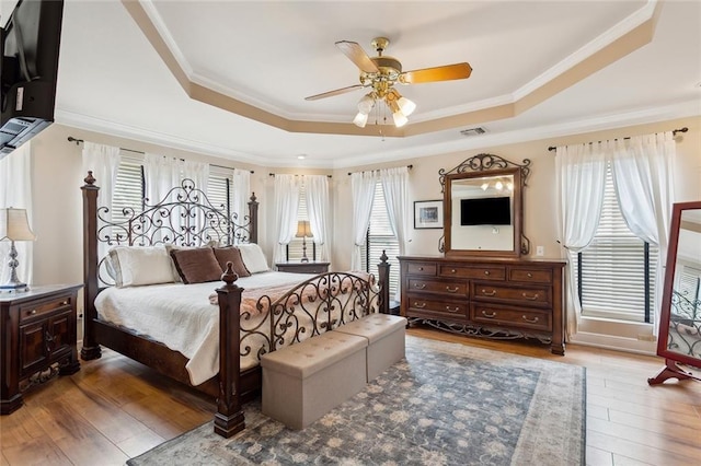 bedroom featuring visible vents, a raised ceiling, ornamental molding, and hardwood / wood-style flooring