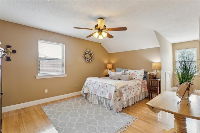 bedroom with baseboards, multiple windows, lofted ceiling, and wood finished floors