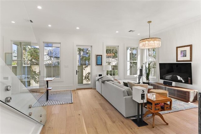 living area with recessed lighting, light wood-type flooring, plenty of natural light, and an inviting chandelier