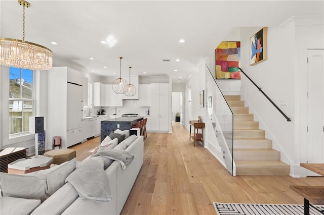 living area with stairway, baseboards, light wood-style flooring, recessed lighting, and a chandelier