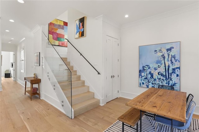 stairs featuring recessed lighting, wood finished floors, baseboards, and ornamental molding