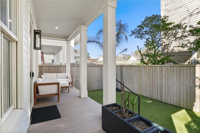 wooden terrace featuring a lawn, an outdoor living space with a fire pit, and a fenced backyard