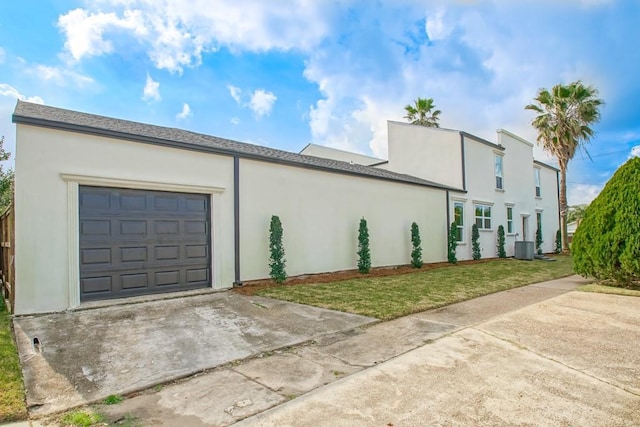 view of property exterior featuring a yard, a garage, driveway, and stucco siding