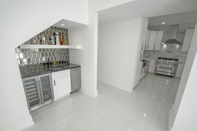 bar featuring indoor wet bar, wall chimney exhaust hood, backsplash, and stainless steel appliances