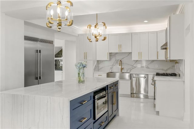 kitchen featuring tasteful backsplash, light stone counters, appliances with stainless steel finishes, an inviting chandelier, and a sink