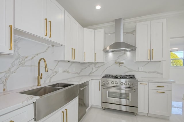 kitchen with light stone countertops, a sink, stainless steel appliances, white cabinets, and wall chimney range hood