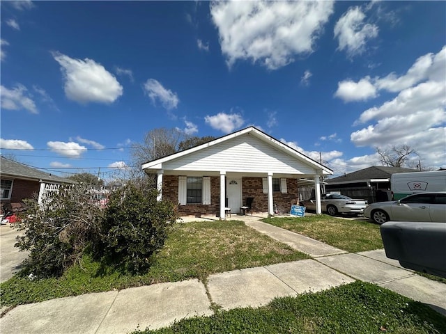 bungalow-style home featuring brick siding, covered porch, and a front lawn