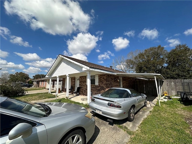 view of side of home with brick siding, an attached carport, and fence