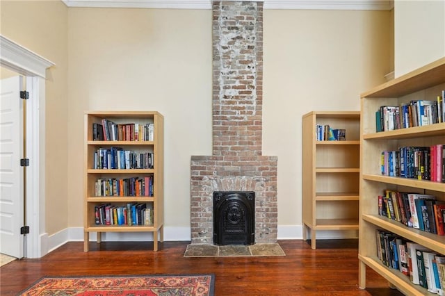 sitting room with baseboards, wood finished floors, a fireplace, and ornamental molding