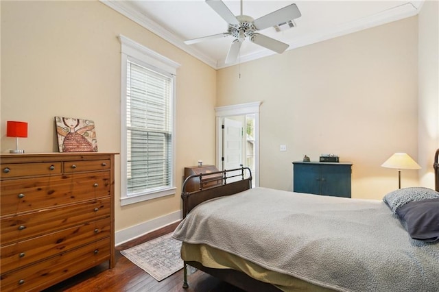 bedroom with wood finished floors, visible vents, baseboards, ceiling fan, and crown molding