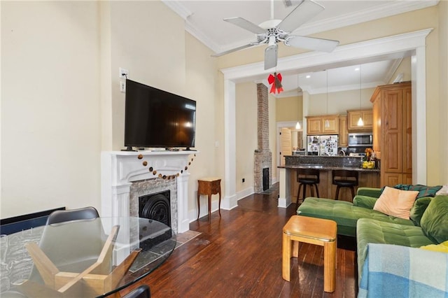 living area with baseboards, ceiling fan, a fireplace with flush hearth, ornamental molding, and dark wood-style floors