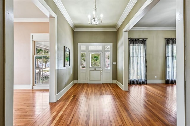 foyer with baseboards, a chandelier, ornamental molding, and hardwood / wood-style flooring