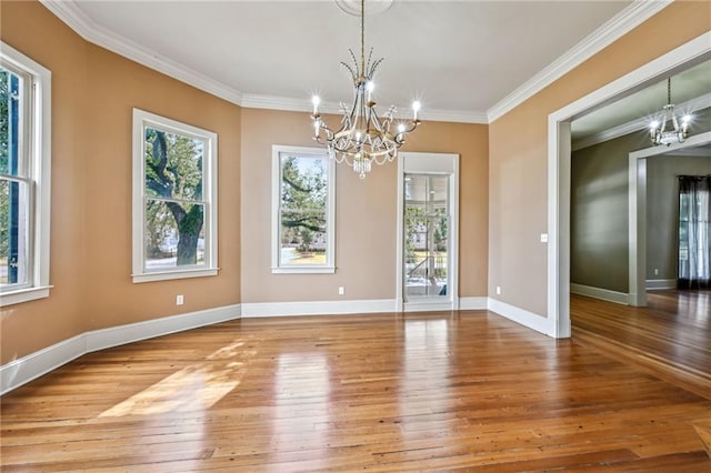 unfurnished dining area featuring an inviting chandelier, baseboards, wood-type flooring, and ornamental molding