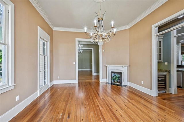 unfurnished living room with a fireplace with flush hearth, beverage cooler, ornamental molding, hardwood / wood-style flooring, and baseboards