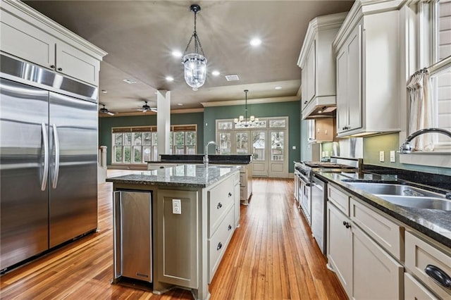 kitchen featuring a sink, decorative light fixtures, high quality appliances, and light wood finished floors