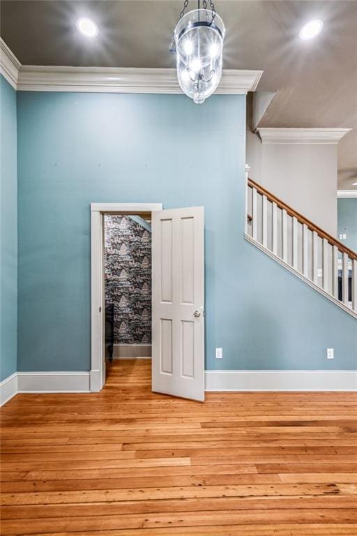 spare room featuring light wood-type flooring, stairs, crown molding, and baseboards