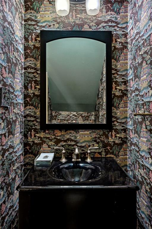 bathroom with wallpapered walls and vanity