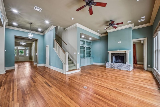 unfurnished living room with built in features, wood-type flooring, a fireplace, baseboards, and stairs