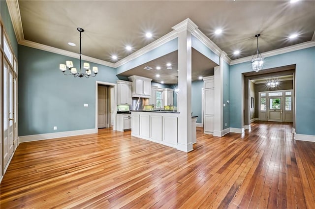 kitchen featuring light wood-type flooring, dark countertops, white cabinets, baseboards, and a chandelier