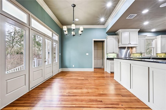 kitchen with visible vents, a notable chandelier, ornamental molding, dark countertops, and white cabinets