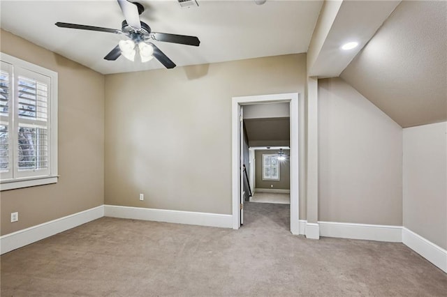 unfurnished bedroom with light carpet, ceiling fan, lofted ceiling, and baseboards