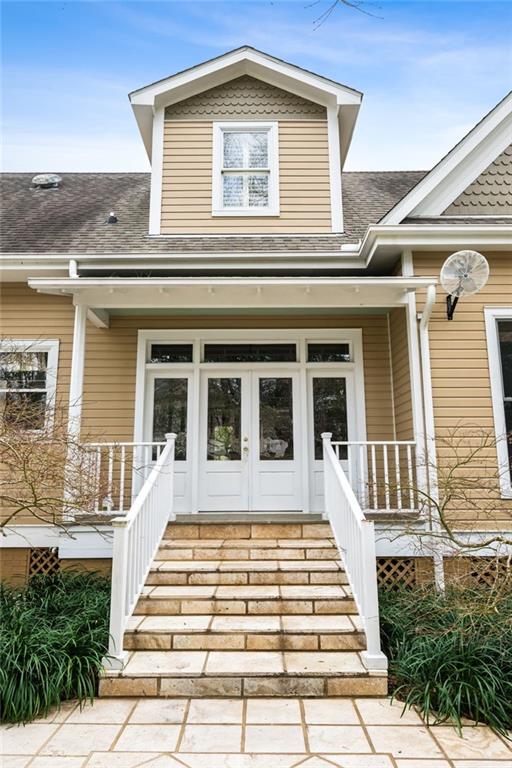 property entrance with a porch, french doors, and roof with shingles