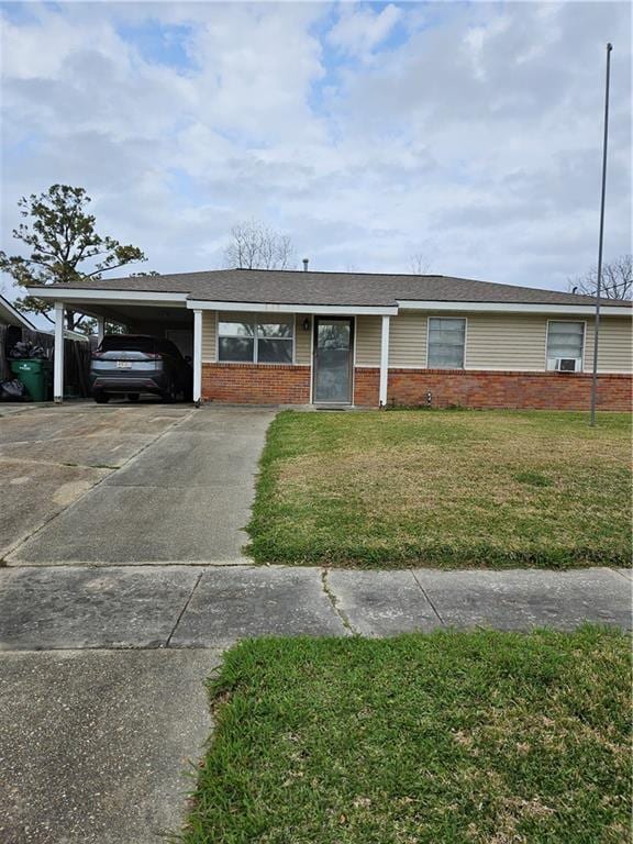 single story home featuring brick siding, an attached carport, concrete driveway, and a front lawn