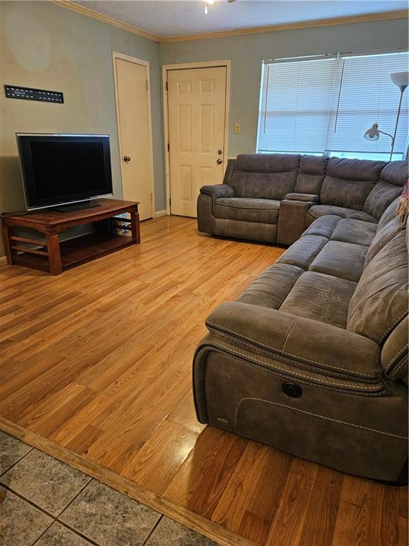 living room with wood finished floors and crown molding