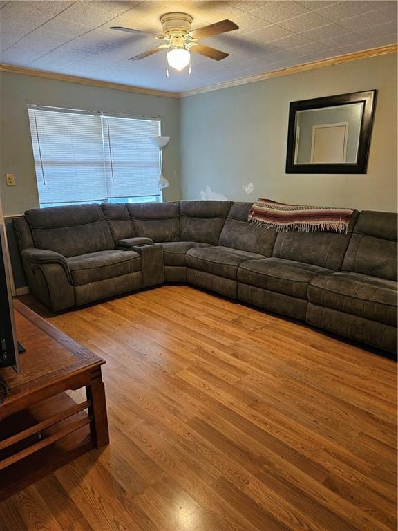 living area with a ceiling fan, wood finished floors, and ornamental molding