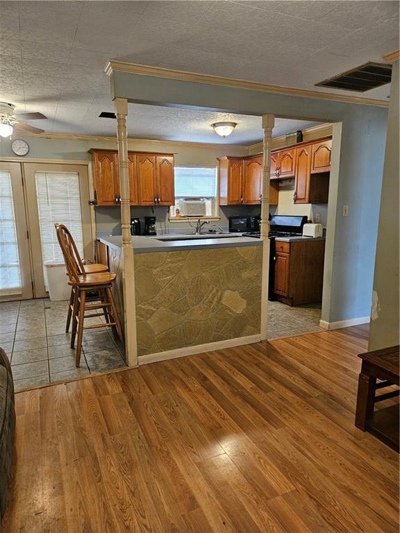 kitchen featuring visible vents, brown cabinets, a peninsula, and light wood-type flooring