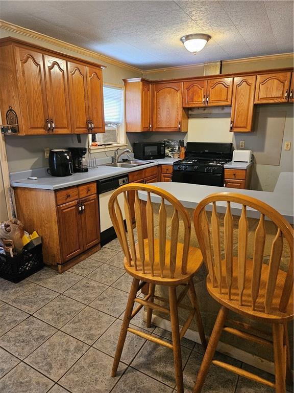 kitchen with a sink, black appliances, light countertops, under cabinet range hood, and brown cabinets