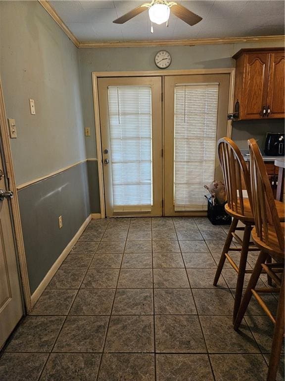 entryway featuring dark tile patterned flooring, ornamental molding, and a ceiling fan